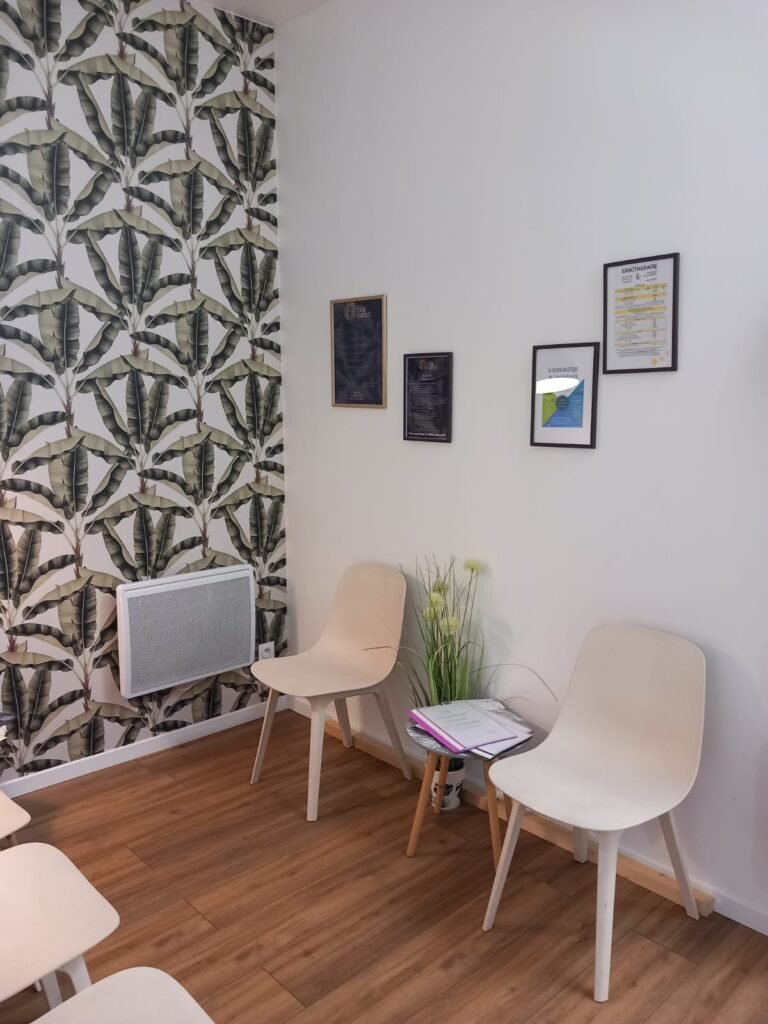 Salle d'attente accueillante du cabinet d'ergothérapie Les Avenières, avec tapisserie tropicale, plantes et bouquet décoratif