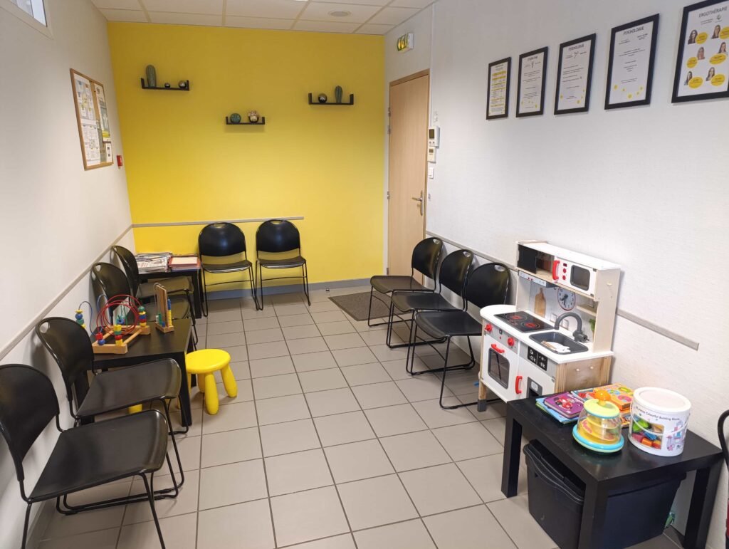 Salle d'attente d'un cabinet d'ergothérapie avec des jeux pour enfants et des sièges pour les parents.